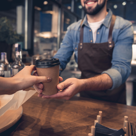 Person serving takeaway coffee in coffee shop