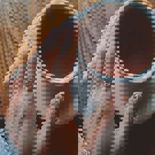 Hand on mug of coffee